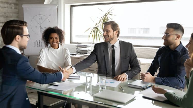 this is an image of business people in suits shaking hands across a table