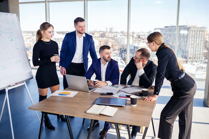 Business People Meeting Around A Table Exchanging Ideas and Smiling