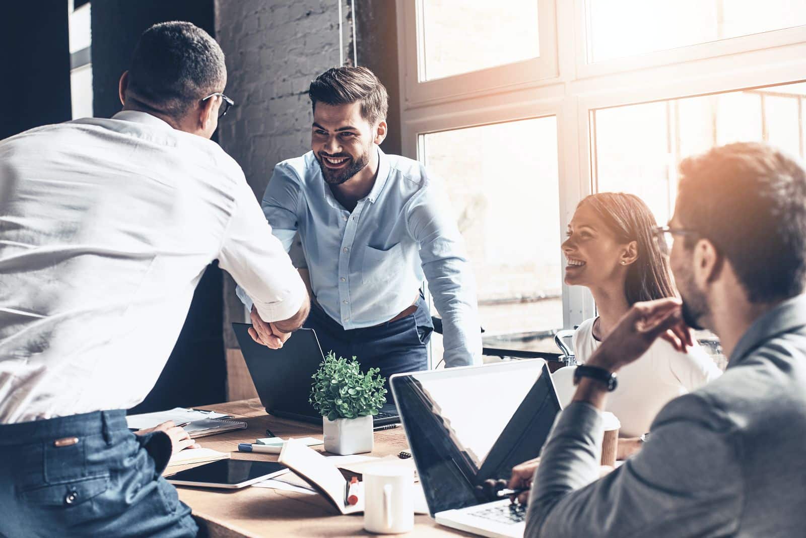 Young business people happily shaking hands